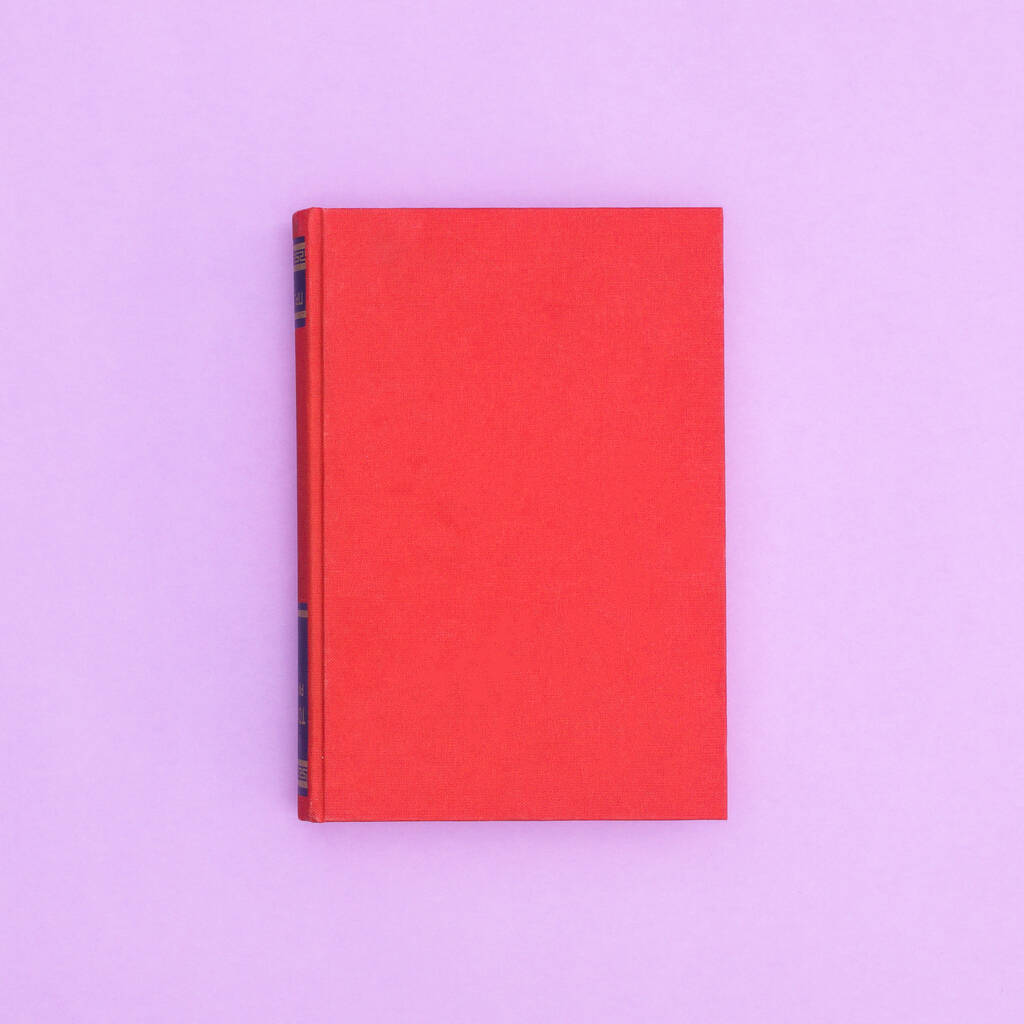 Red hardcover vintage book on pastel purple background. Flat lay copy space - Foto, Bild
