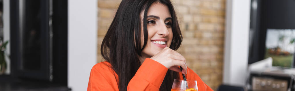 Positive woman holding drinking straw of cocktail in cafe, banner  - Photo, Image
