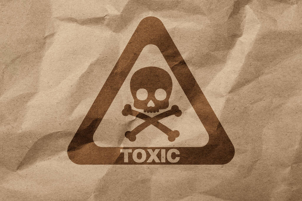 Hazard warning sign (skull-and-crossbones symbol and word TOXIC) on crumpled kraft paper, top view - 写真・画像