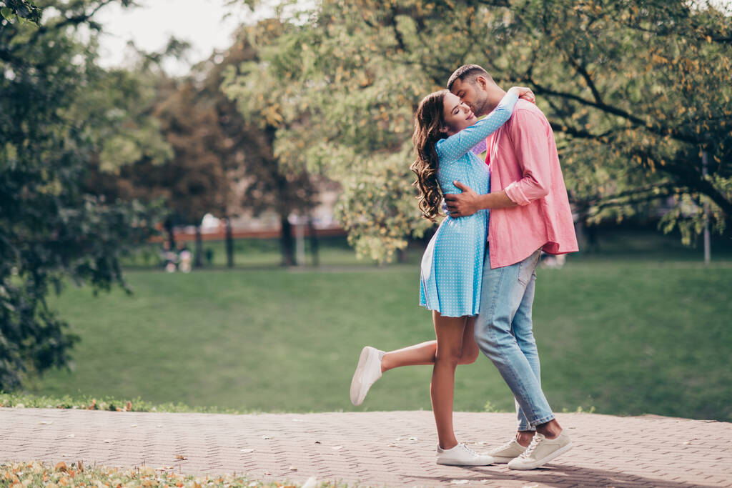 Photo of sweet charming two people together wear casual outfits walking hugging smiling outside garden. - Foto, afbeelding