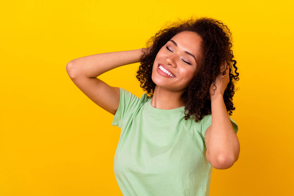 Photo of pretty dreamy girl dressed green t-shirt smiling arms hair empty space isolated yellow color background. - Foto, Imagem