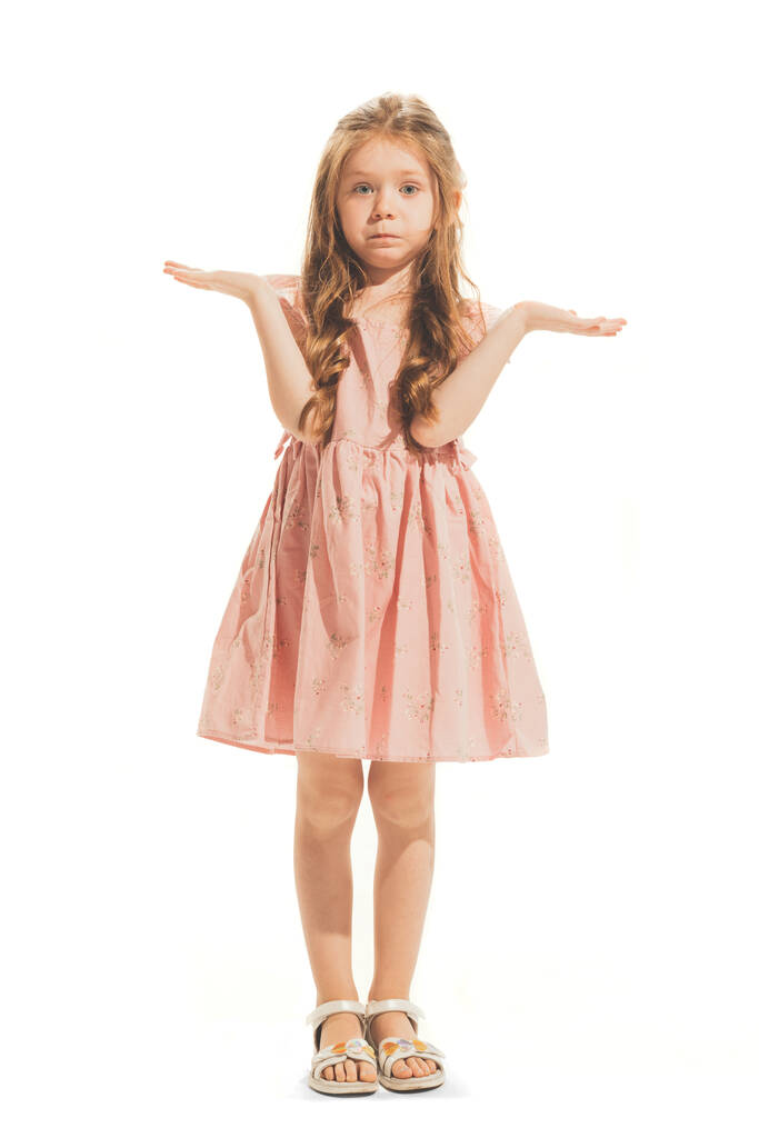 Портрет красивої маленької дівчинки в стильній сукні позує, розтягуючи руки ізольовано на білому студійному фоні. Поняття емоцій, вираження обличчя, дитинство, гра, освіта. Копіювати простір для оголошення
 - Фото, зображення
