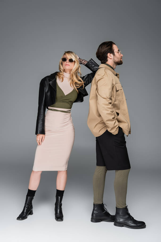 full length of stylish couple in autumnal outfits and posing together on grey - Photo, Image