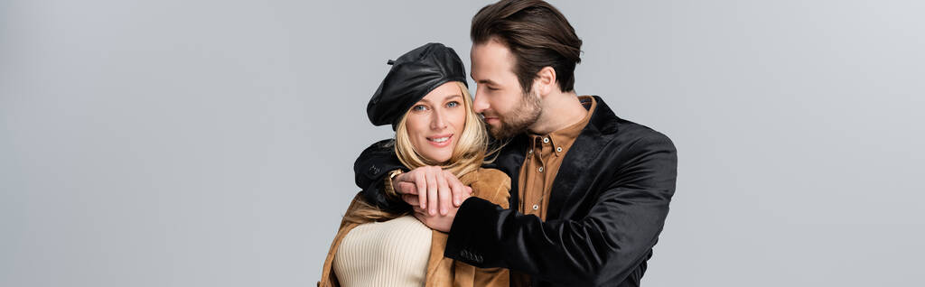 happy man hugging happy blonde woman in stylish beret isolated on grey, banner - Photo, Image