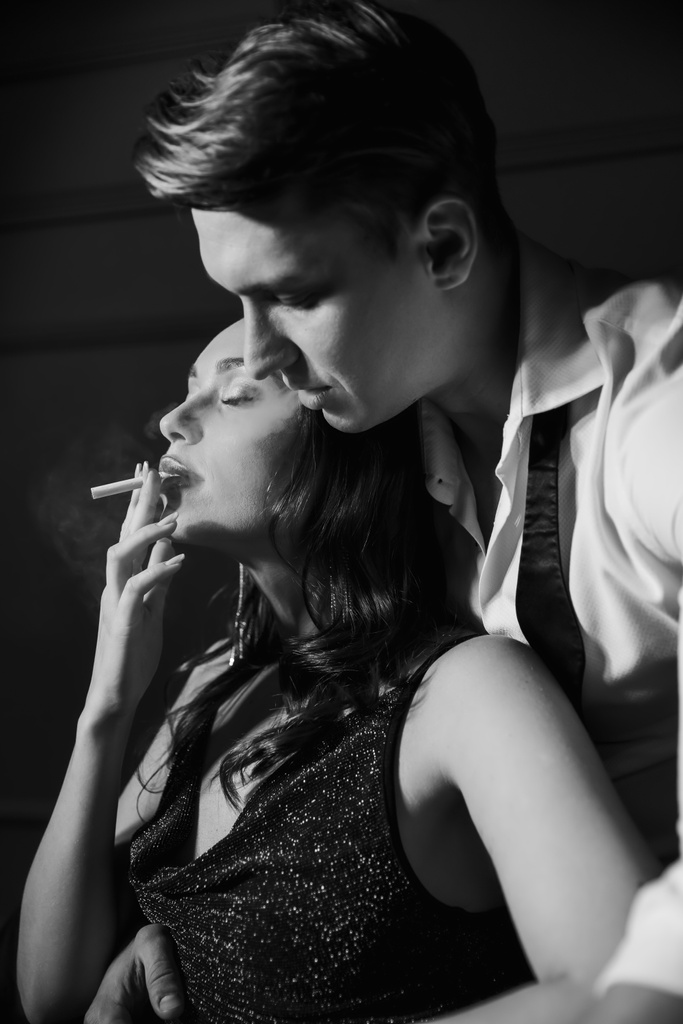 Woman in dress smoking cigarette near boyfriend in shirt at home  - Fotoğraf, Görsel