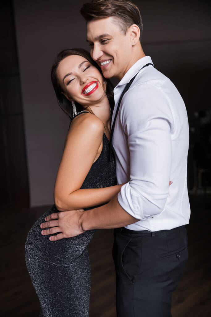 Cheerful woman in dress hugging boyfriend at home  - Valokuva, kuva
