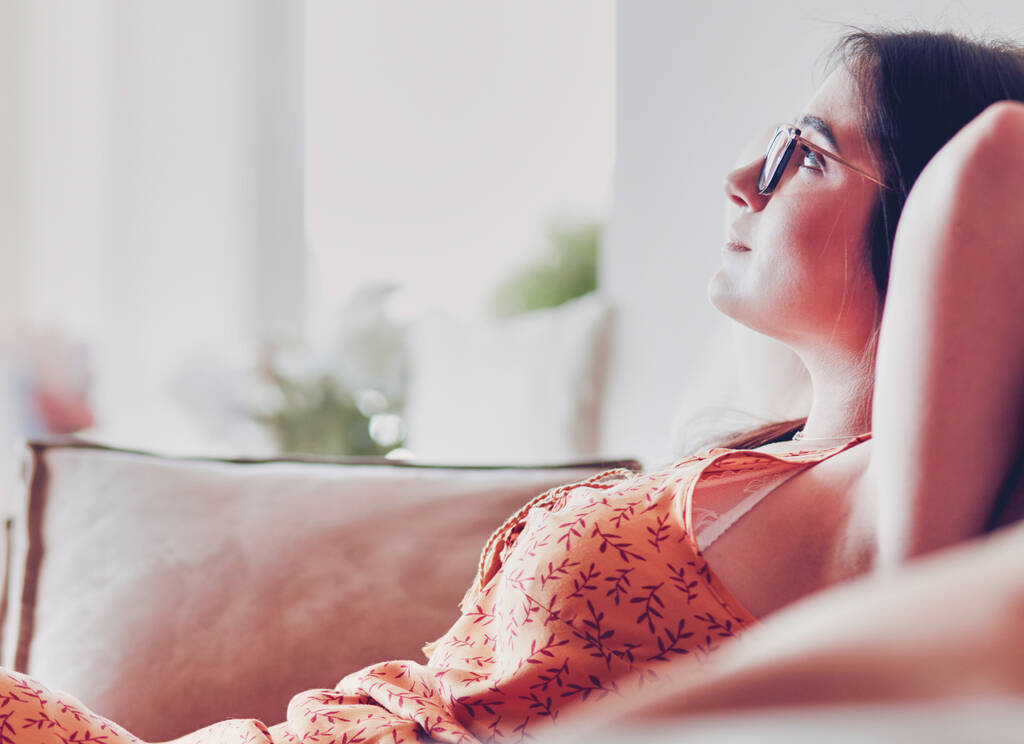 Entspannte Frau sitzt zu Hause auf einem modernen Sofa. - Foto, Bild