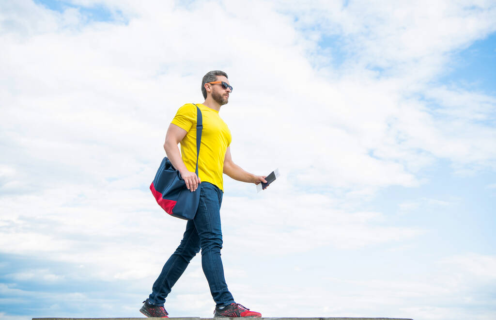 Guy traveler traveling on vacation with travel bag and document sky background, copy space. - Foto, Imagem