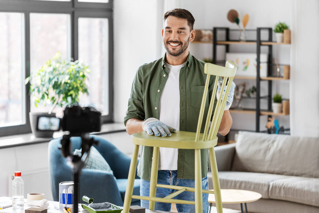 blogging, furniture restoration and home improvement concept - happy smiling man or blogger with camera showing old wooden chair renovation and recording tutorial video - Valokuva, kuva