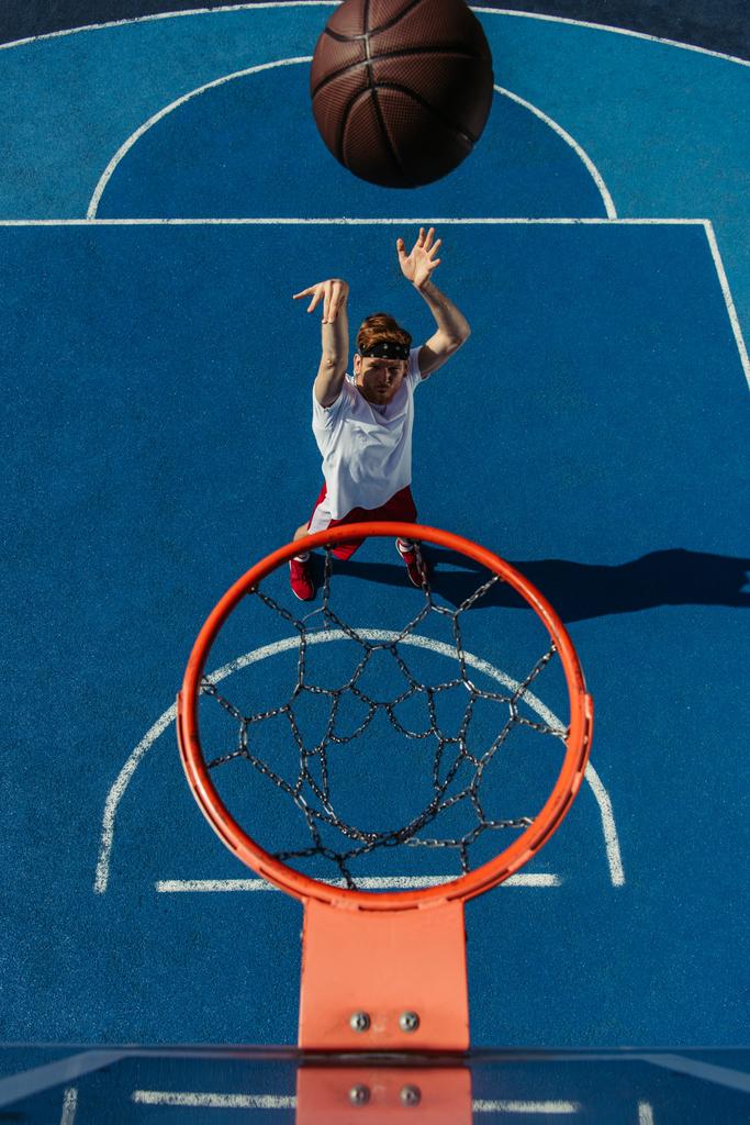 top view of man throwing ball into basketball hoop - 写真・画像