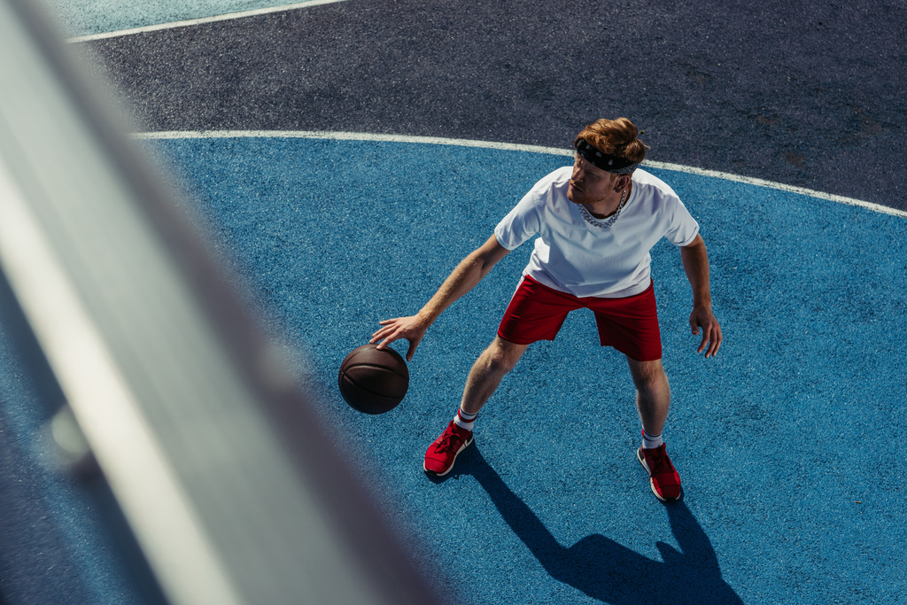 high angle view of sportive man playing basketball on court on blurred foreground - Photo, Image