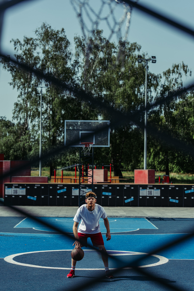 full length of basketball player training on modern court on blurred foreground - Valokuva, kuva