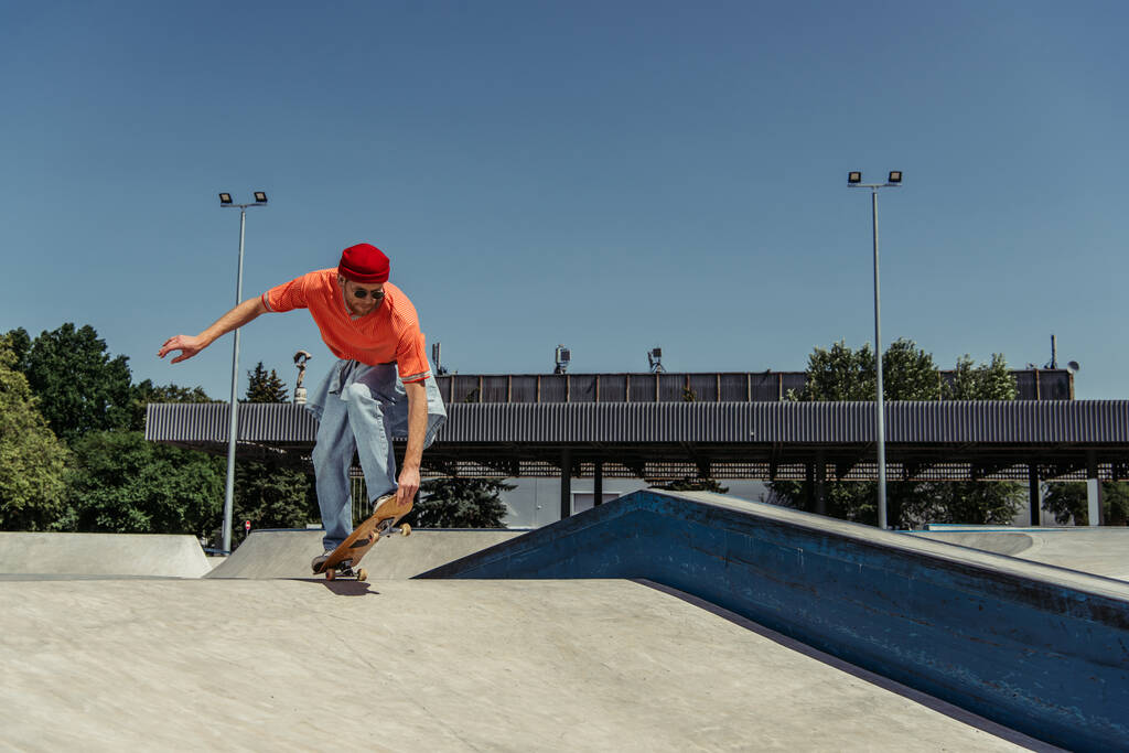 young man in stylish clothes skateboarding on ramp in park - Foto, immagini