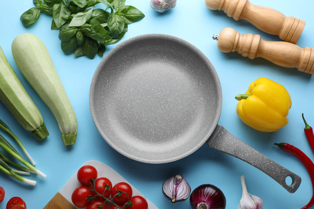 Плоска композиція з сковородою та свіжими продуктами на світло-блакитному фоні
 - Фото, зображення