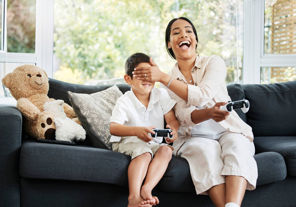 Mother and son playing video games, having fun and enjoying quality time together. Cheerful, bonding and carefree child and parent using a gaming console or interactive modern technology. - Photo, Image