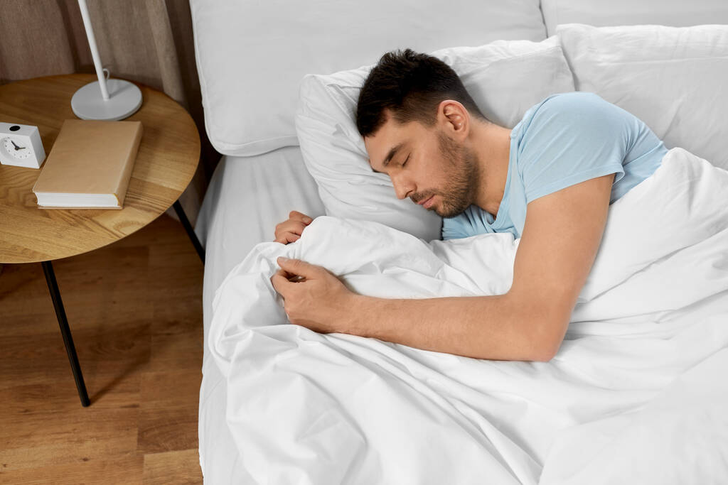 lidé, spaní a odpočinek koncept - muž spí v posteli doma - Fotografie, Obrázek