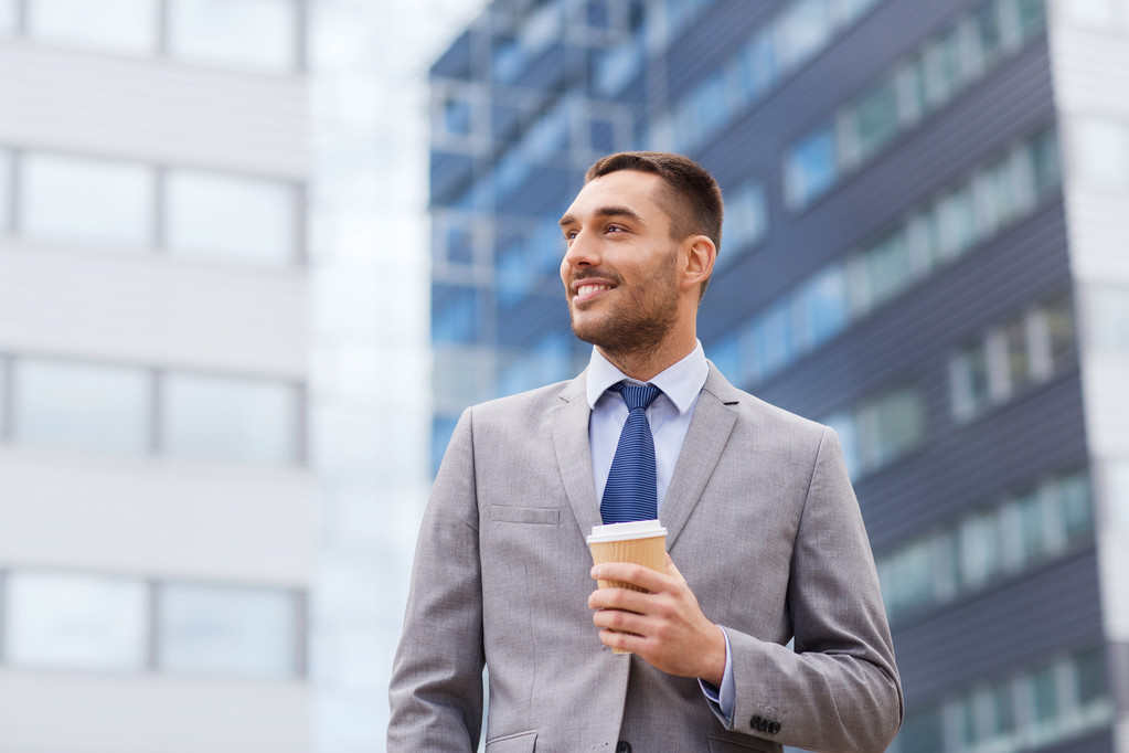 молодий усміхнений бізнесмен з паперовою чашкою на відкритому повітрі
 - Фото, зображення