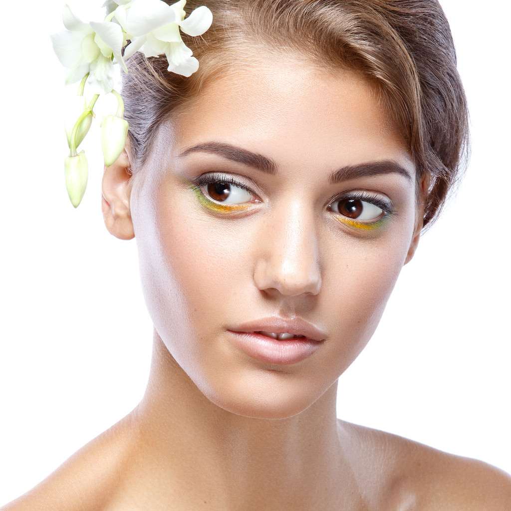 Mujer joven con la cara clara natural componen su cabello con una flor blanca sobre un fondo claro
 - Foto, imagen