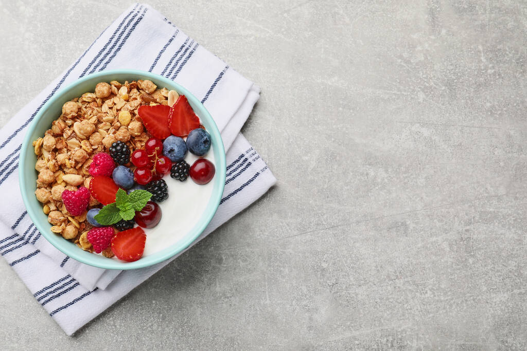 Flat lay composition with tasty granola and berries on light grey table. Space for text - Fotó, kép