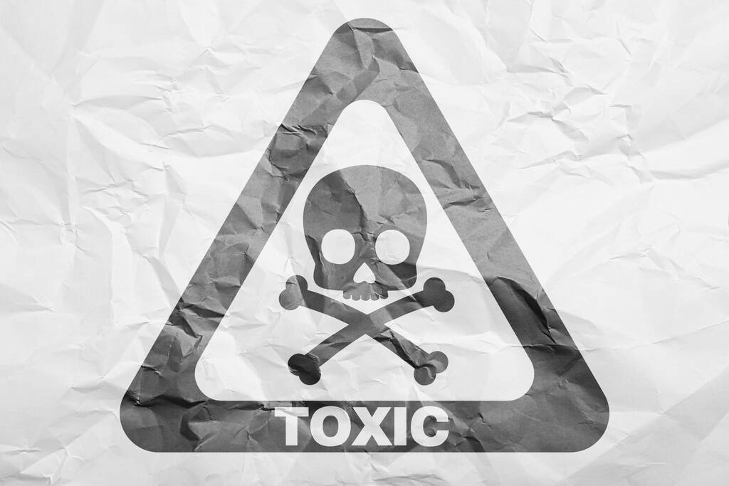 Σήμα προειδοποίησης κινδύνου (σύμβολο κρανίου και διασταυρωμένων οστών και λέξη TOXIC) σε τσαλακωμένο λευκό χαρτί, πάνω όψη - Φωτογραφία, εικόνα