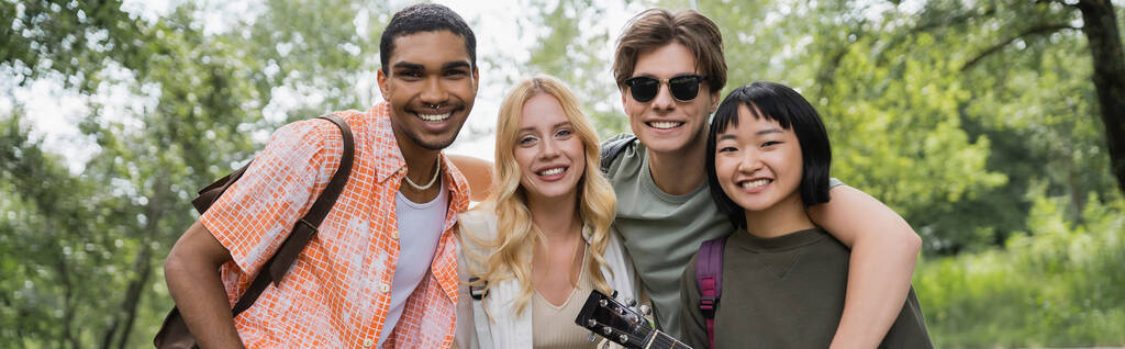 young and cheerful multiethnic tourists looking at camera in countryside, banner - Foto, immagini