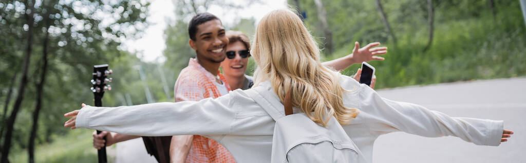 blonde woman with outstretched hands running towards interracial friends, banner - Photo, Image