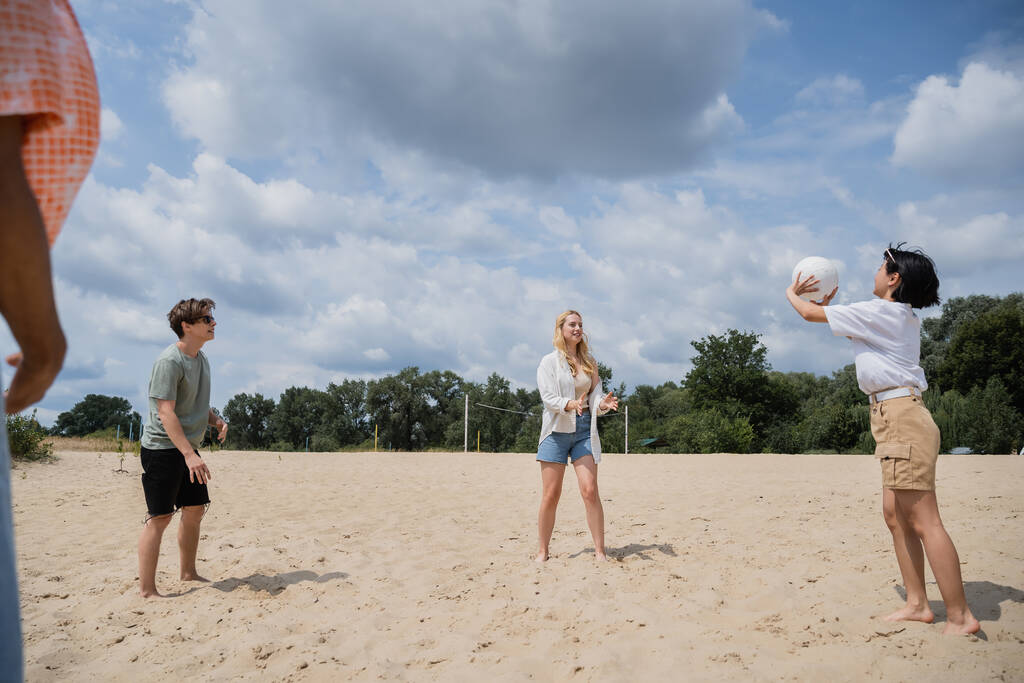 молоді багатоетнічні друзі грають у волейбол на піщаному пляжі влітку
 - Фото, зображення