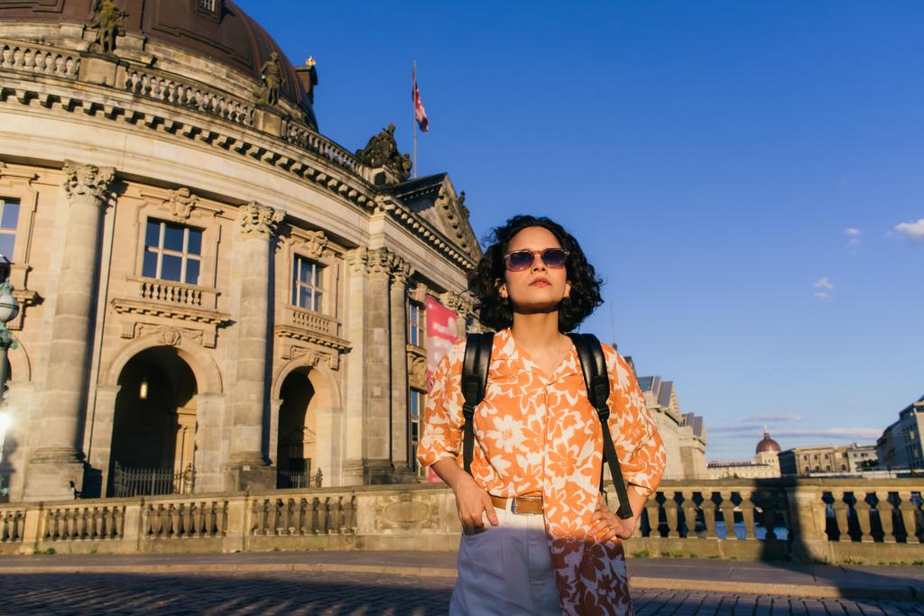стильная молодая женщина в солнцезащитных очках, стоящая возле музея в Берлине  - Фото, изображение