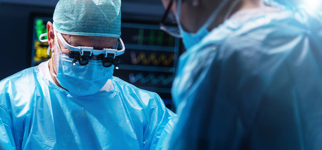 Diverse team of professional medical surgeons perform surgery in the operating room using high-tech equipment. Doctors work to save a patient in a modern hospital. The concept of medicine, technology - Valokuva, kuva