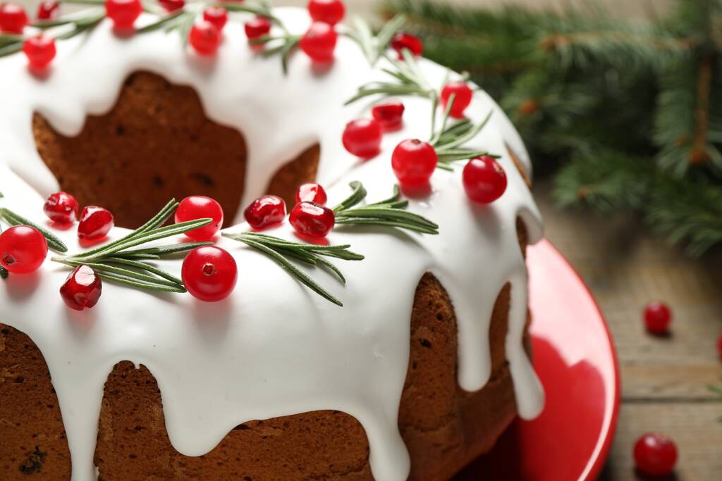 Традиційний різдвяний торт, прикрашений глазур'ю, насінням граната, журавлиною і розмарином на столі, крупним планом
 - Фото, зображення