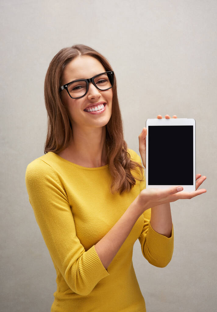 This is how I stay connected. Studio portrait of an attractive young woman posing with her tablet against a grey background - Foto, immagini
