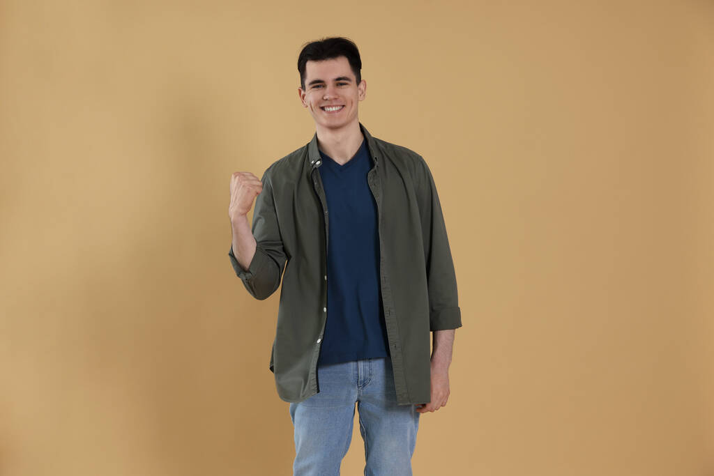 Portrait of happy young man on beige background - Photo, Image