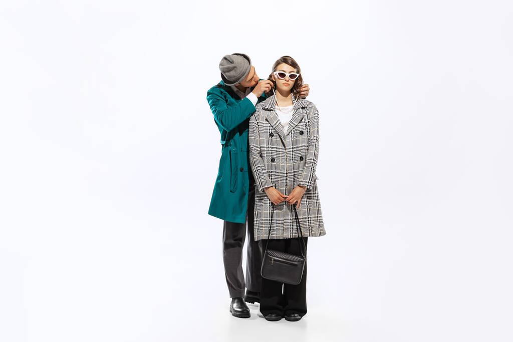 Relationships, love, care. Young married couple, handsome man and woman in 70s, 80s fashion style attires isolated on white background. Concept of season fashion, art, music, style, ad - Foto, afbeelding