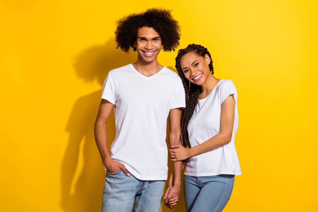 Photo of two lovely positive people hold arms toothy beaming smile isolated on yellow color background. - Fotó, kép