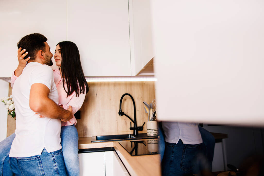 Ευτυχισμένο ζευγάρι ερωτευμένο να στέκεται στην κουζίνα ρομαντικά. Μεγάλη αγάπη στα μάτια τους. Υψηλής ποιότητας φωτογραφία - Φωτογραφία, εικόνα