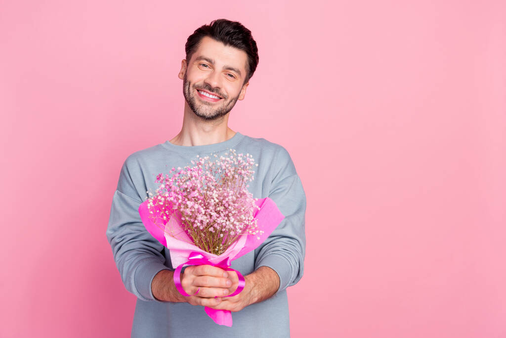 Портрет положительного человека руки держать свежие цветы букет изолирован на розовом фоне цвета. - Фото, изображение