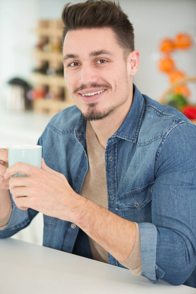 молодий чоловік насолоджується чашкою кави вдома
 - Фото, зображення