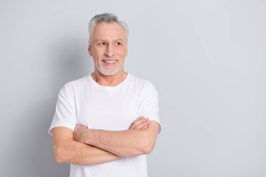 Φωτογραφία από αστείο ηλικιωμένος άνδρας σταυρωμένα χέρια ματιά promo φορούν λευκό t-shirt που απομονώνονται σε γκρι φόντο χρώμα. - Φωτογραφία, εικόνα