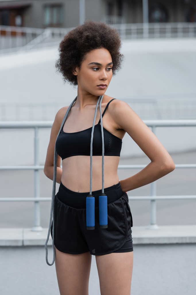 Fit african american sportswoman with jump rope looking away on stadium  - Photo, image