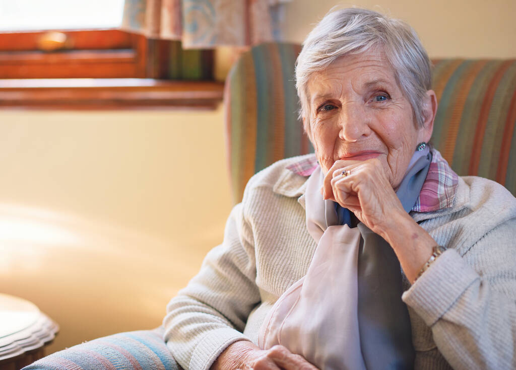Πορτρέτο ευτυχισμένη ηλικιωμένη γυναίκα χαμογελώντας κάθεται στον καναπέ στο σπίτι απολαμβάνοντας συνταξιοδότηση. - Φωτογραφία, εικόνα