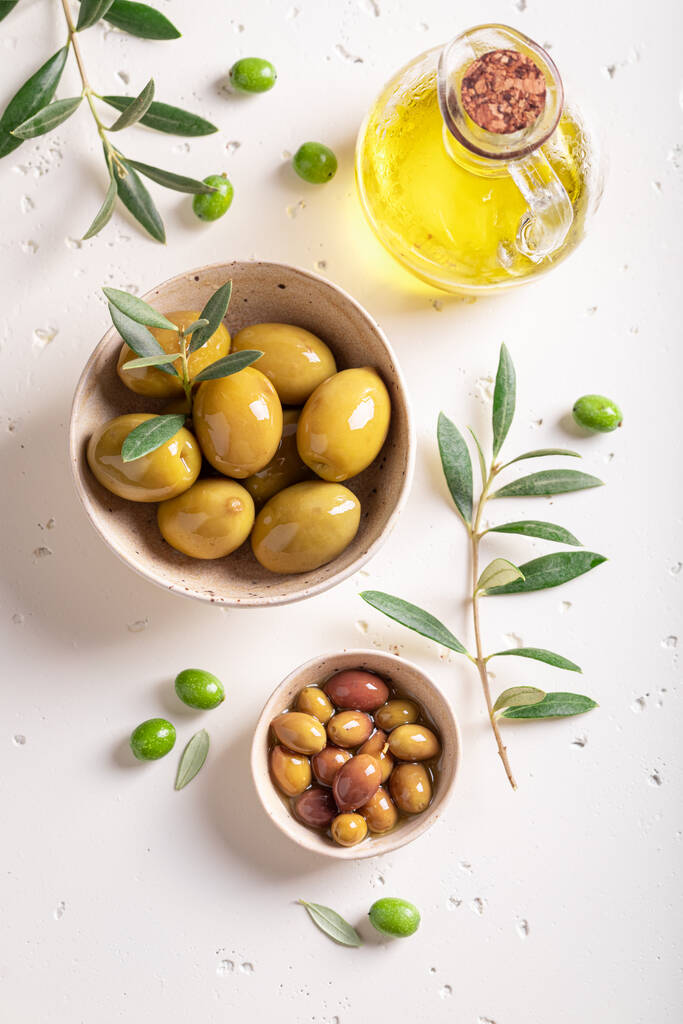 Various types of olives in bowl with an olive branch. Products made of olives. - Photo, image