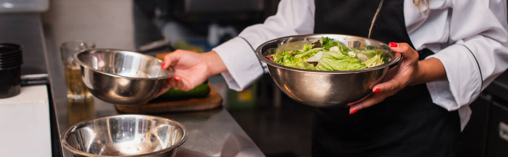 cropped view of african american chef holding bowl with salad in professional kitchen, banner - Foto, immagini