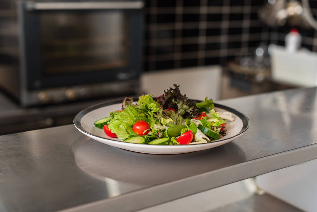 тарілка зі свіжоприготованим салатом на професійній кухні
 - Фото, зображення