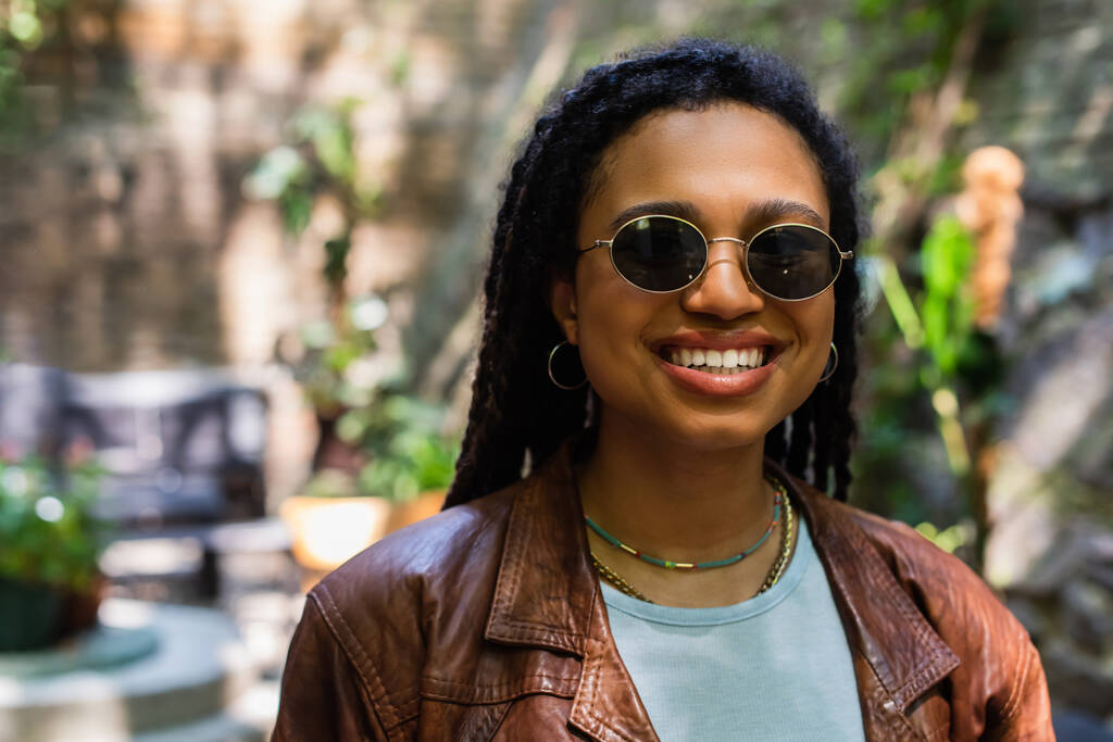 portrait of happy african american woman in sunglasses smiling outside - Fotó, kép