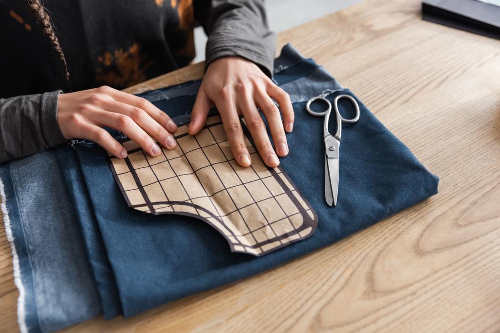 Обрезанный вид африканского американского дизайнера, держащего швейный узор рядом с тканями и ножницами  - Фото, изображение