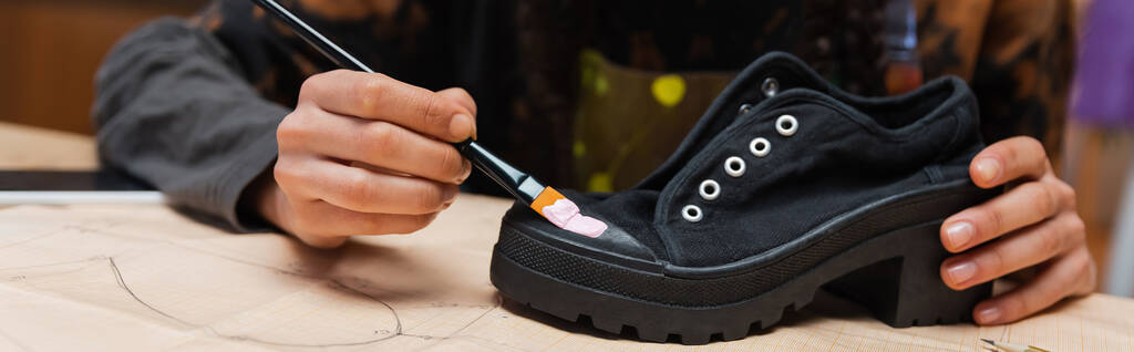 Partial view of african american craftswoman painting on shoe on sewing pattern, banner  - Foto, immagini