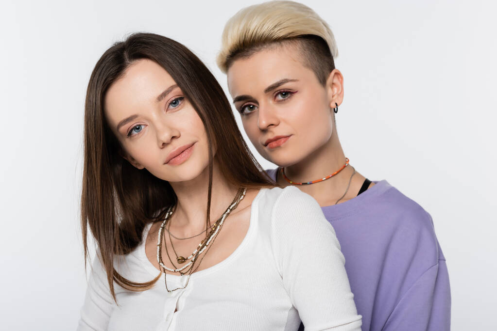 pretty and trendy lesbian couple with makeup looking at camera isolated on grey - Fotoğraf, Görsel