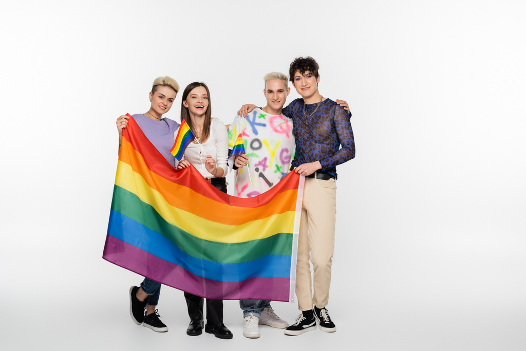full length of diverse identity friends standing with lgbtq flags on grey background - Foto, imagen