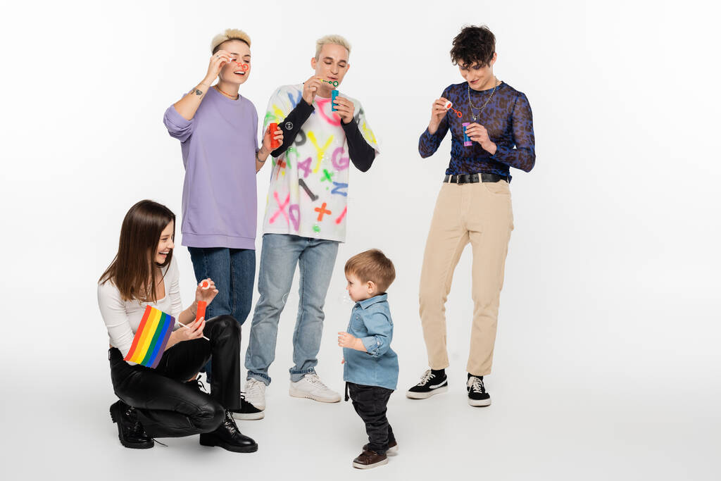 happy lesbian woman with rainbow flag near toddler boy and lgbtq community friends on grey background - Photo, Image