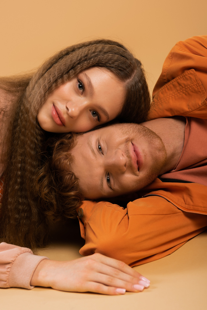 happy and young redhead man lying together with pretty girlfriend isolated on beige - Fotoğraf, Görsel
